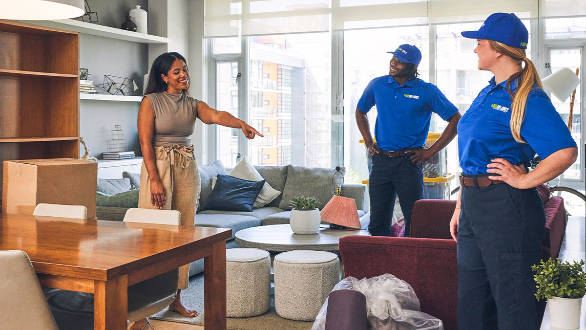 1-800-GOT-JUNK? truck team member removing bulky items as homeowners are packing boxes during a move.
