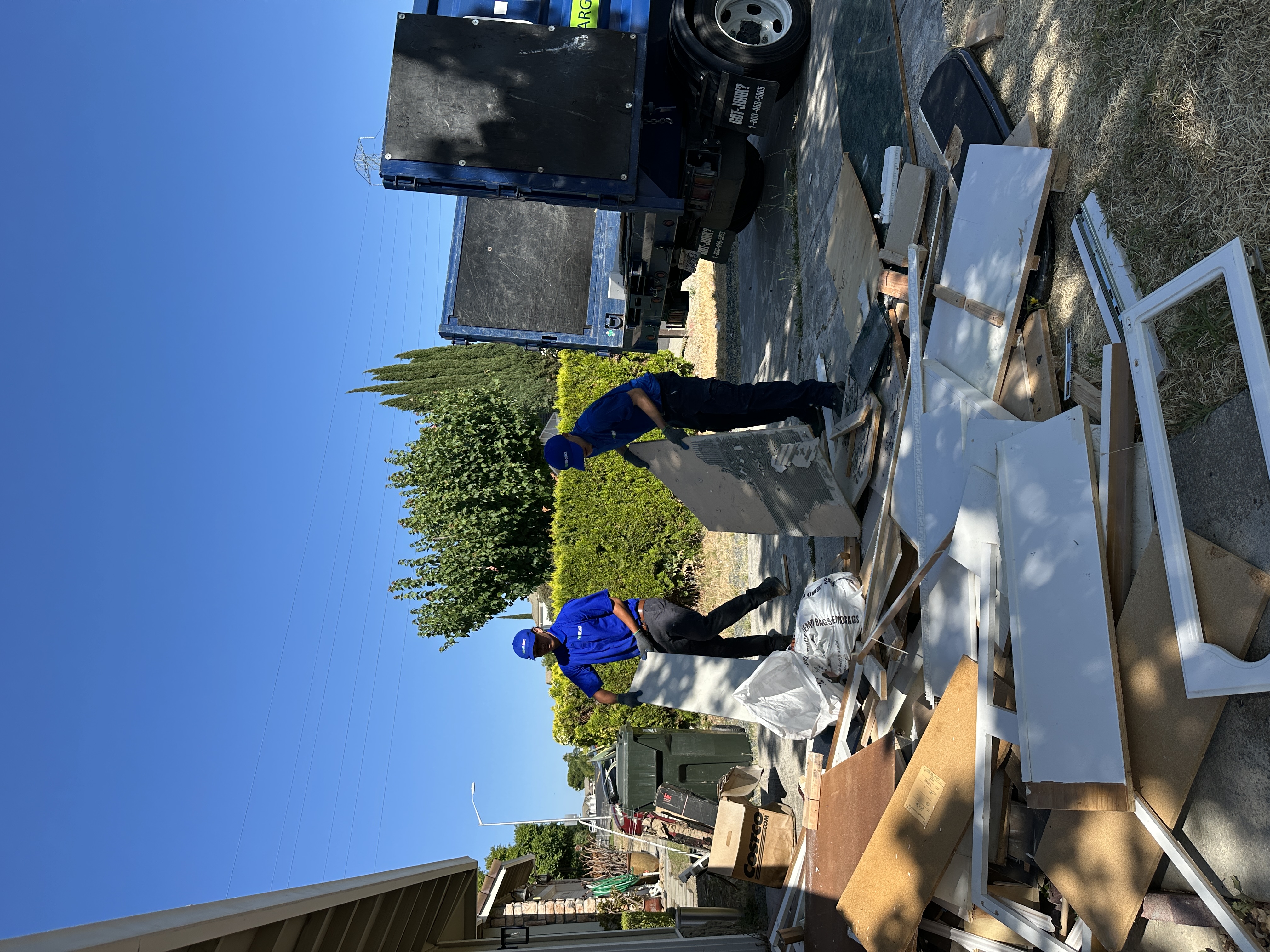 Two 1-800-GOT-JUNK? team members loading kitchen renovation debris into a truck during a junk removal service in Antioch, CA.