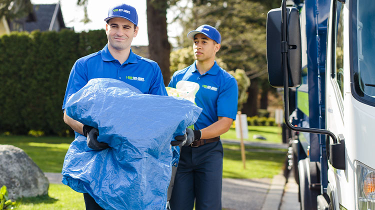 Two 1-800-GOT-JUNK? team members carrying various junk to the truck