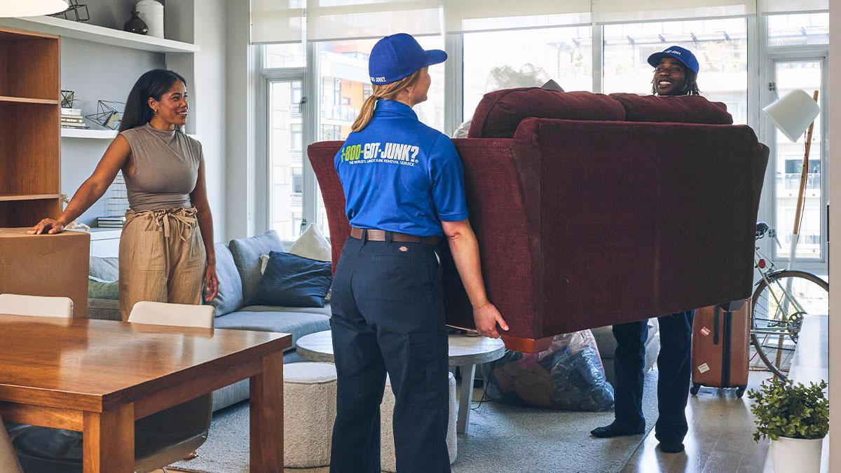 1-800-GOT-JUNK? truck team members removing boxes filled with clutter from a residential property.