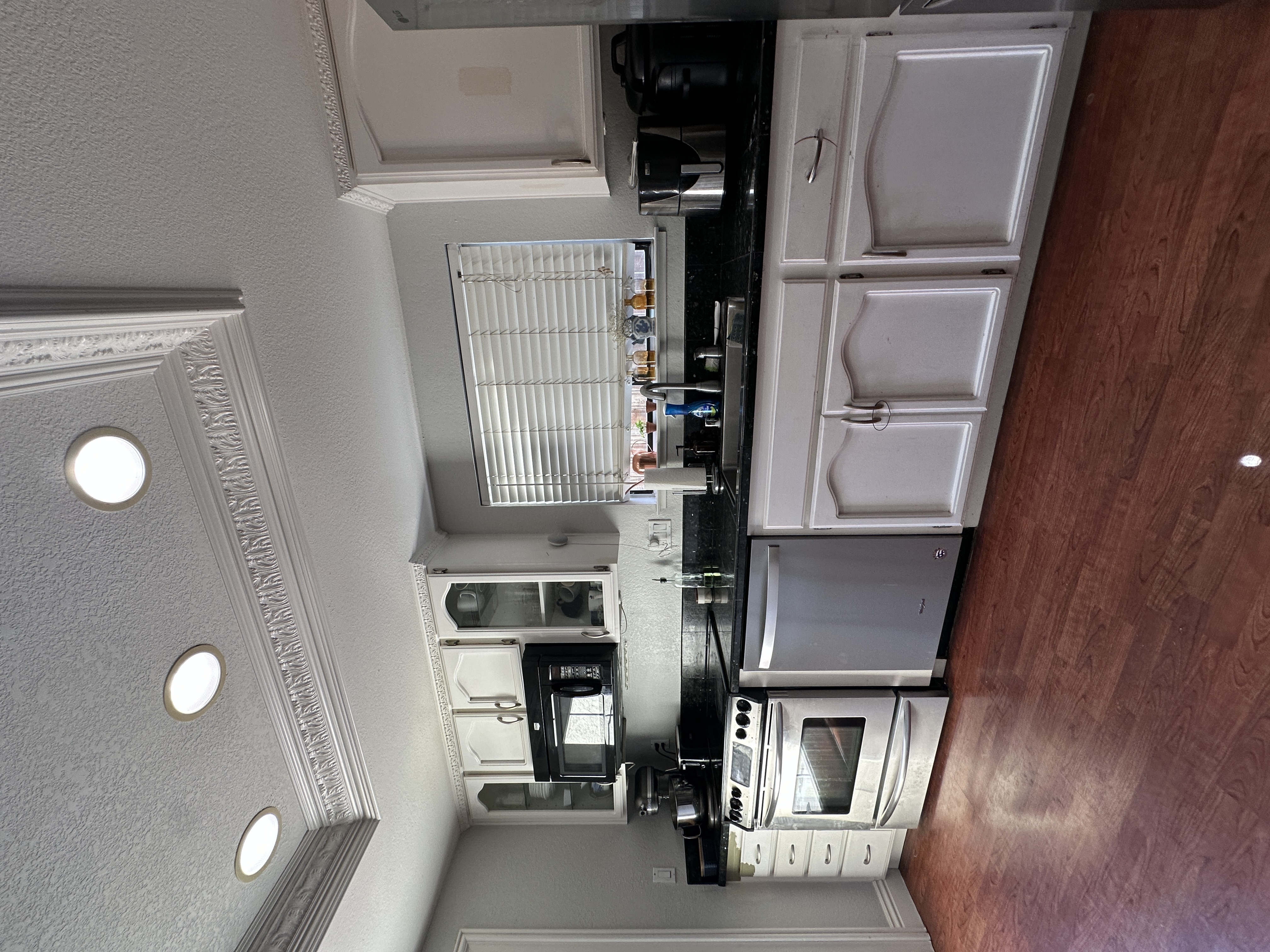 Original kitchen before renovation, showing white cabinets, black countertops, and appliances, in Antioch, CA.