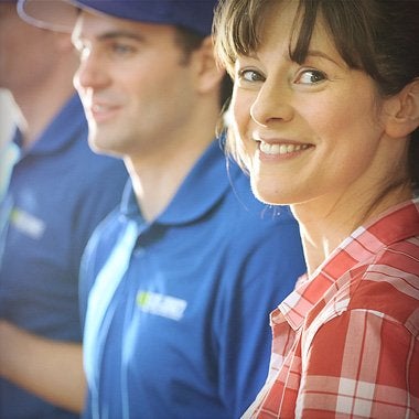 Smiling 1-800-GOT-JUNK? customer hearing junk removal price from uniformed 1-800-GOT-JUNK? employees