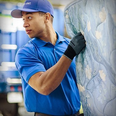 1-800-GOT-JUNK? team member picking up a mattress for disposal